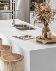 Lumara cheese plate in solid natural wood with round profile, visible timber grain and low pedestal feet.