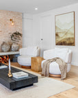 Pair of KULALA Living Swivel Chairs in a contemporary living room, styled with a black timber coffee table, neutral rug, and natural pottery against a textured brick wall.
