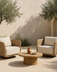 Pair of Malusi One Seater outdoor armchairs in natural wicker with cream cushions, styled with a round timber coffee table in a Mediterranean courtyard