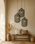 Trio of black mansa Pendants by KULALA Living, handcrafted from woven steel wire mesh with sculptural organic forms, styled in a warm neutral entryway with bench seat, textured cushions and pampas grass in a clay vessel