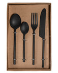 A sophisticated matte black cutlery set presented in a minimalist kraft box, featuring a modern fork, knife, tablespoon, and teaspoon with sleek, contemporary handles