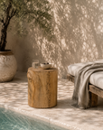 Natural Meera stool crafted from magnesium oxide styled beside a poolside daybed creating a warm organic retreat with rustic character and natural textures.