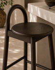 Milo barchair in espresso finish styled beside a textured stone island creating a warm refined kitchen setting with natural earthy tones.