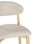 Contemporary wooden barstool with a natural timber frame and an upholstered seat and backrest in neutral fabric, blending comfort and style for modern interiors.