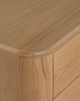 Molly Bedside Table in natural oak with rounded edges and two drawers, styled in a minimalist bedroom setting