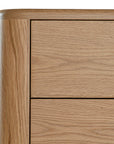 Molly Bedside Table in natural oak with rounded edges and two drawers, styled in a minimalist bedroom setting