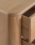 Molly Bedside Table in natural oak with rounded edges and two drawers, styled in a minimalist bedroom setting
