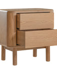 Molly Bedside Table in natural oak with rounded edges and two drawers, styled in a minimalist bedroom setting