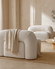 Nash occasional chair in pearl bouclé styled in a neutral lounge with curved forms, a round timber coffee table, and soft natural light.