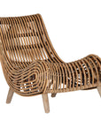 A sculptural natural rattan lounge chair with a curved, low-profile silhouette and sleek wooden legs. The woven design adds texture, while the deep seat and ergonomic shape offer comfort and relaxation