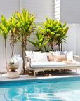 Natural rope outdoor sofa with white cushions, styled with neutral throw pillows by a poolside, creating a relaxed coastal vibe