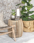 Coastal decor with a natural wooden slatted side table, woven armchair, and indoor plants