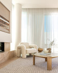Noah Sofa in natural linen paired with the sculptural Side Table in a contemporary lounge room with curved walls and sheer curtains
