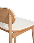 A contemporary bar stool featuring a natural oak frame with a curved white upholstered seat and backrest, designed for modern kitchens and dining spaces