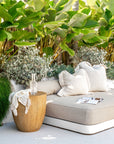 Outdoor daybed styled with soft neutral cushions, a magnesium oxide side table, and a throw, surrounded by lush tropical greenery for a serene, resort-style setting.