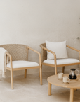 Pair of natural rope and teak armchairs with white cushions in a minimal outdoor setting, styled with a timber coffee table and ceramic decor