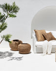 Outdoor setting featuring handwoven seagrass cushions and baskets, styled on a white sofa with a soft throw, creating a natural, relaxed atmosphere