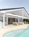 A luxurious outdoor setting by Kulala Living featuring teak lounge chairs with white cushions, a rattan coffee table, and a serene poolside backdrop. The perfect space for relaxed alfresco living