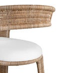 A natural rattan dining chair with a curved backrest and a white upholstered cushion. The woven design and sturdy frame create a stylish and comfortable seating option, perfect for modern coastal or relaxed interiors