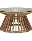 A stylish round dining table featuring a sculptural wooden base with a clear glass top, offering a contemporary yet natural aesthetic for modern dining spaces.
