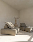 Earthy lounge setting featuring a rustic clay vase with branch arrangement, complemented by natural-toned low-profile lounge seating and a relaxed, minimalist aesthetic.