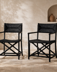 Saga black rattan dining chairs with woven seats and backs, styled as a pair in a warm neutral interior with textured plaster walls and soft natural light.