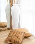Seagrass floor cushions styled with a textured white vase and rustic wooden mirror, creating a natural and organic aesthetic in a serene space