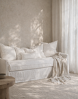 Sirocco three seat sofa in white with soft linen texture styled in a calm sunlit living room with layered neutral cushions and draped throw.