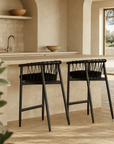 Pair of Sumbe Bar Chairs in black rope and black timber finish styled at a natural stone kitchen island with Mediterranean curves and soft neutral tones
