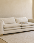 Tash Sofa upholstered in soft polyester fabric styled in a modern neutral living room with a timber side table, indoor plant, and natural light