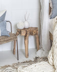 A natural teak root side table styled in a serene bedroom setting, complemented by soft linens, woven textures, and neutral tones for an organic, relaxed aesthetic