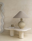 Kulala Living textured paper mache table lamp with a linen shade, styled on an organic stone coffee table. A serene and sculptural lighting accent for modern interiors