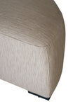 Curved upholstered ottoman with natural textured fabric and subtle black feet, ideal for contemporary living spaces