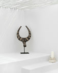 A bold tribal horn sculpture styled in a serene white bathroom, paired with soft candlelight, creating a tranquil yet artistic interior statement.