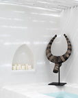A bold tribal horn sculpture styled in a serene white bathroom, paired with soft candlelight, creating a tranquil yet artistic interior statement.