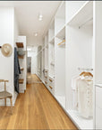Minimalist bedroom with natural wooden flooring, and large white walk-in-robe creating a bright and airy atmosphere.