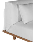 A contemporary armless sofa with plush white cushions and a sturdy natural teak wood frame. This minimalist lounge piece offers versatile seating, perfect for modern living spaces or outdoor settings