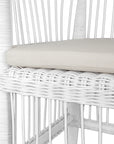 A beautifully crafted white rattan armchair with an open-weave design and a white cushioned seat, perfect for adding a relaxed coastal touch to any space