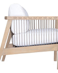 Wooden accent chair with white cushions and sleek spindle detailing, perfect for modern coastal and relaxed living spaces