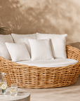 Zambezi Daybed handcrafted from natural rattan with white cushions, styled in an outdoor lounge with warm neutral tones and soft sunlight