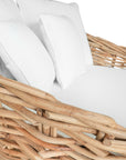 Natural wicker daybed with plush white cushions, creating a relaxed coastal vibe.