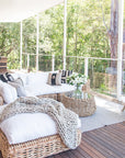Natural wicker ottoman with a plush white cushion, creating a relaxed coastal vibe in outdoor setting.