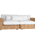Natural wicker corner chair with thick white cushions, showcasing a coastal-inspired design perfect for indoor and outdoor settings
