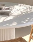 Coastal-inspired dining space featuring curved rattan dining chairs, paired with a white fluted dining table. Styled with candle holders, neutral-toned decor with organic ambiance