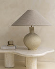 Kulala Living textured paper mache table lamp with a linen shade, styled on an organic stone coffee table. A serene and sculptural lighting accent for modern interiors