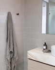 Wall-mounted towel hook in a minimalist neutral toned bathroom and vanity.