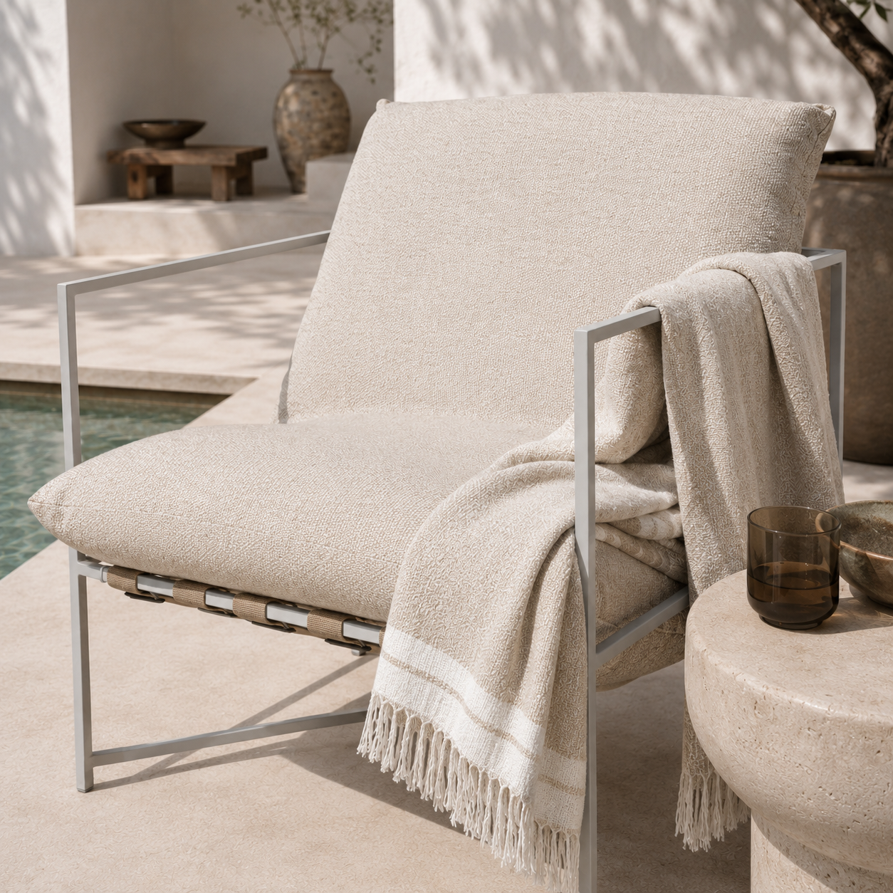 Beige lounge chair with a blanket draped over it in an outdoor setting.