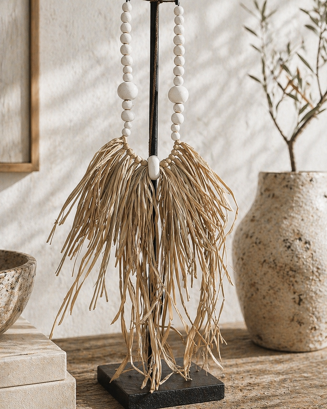 Decorative item with white beads and dried grasses on a wooden surface
