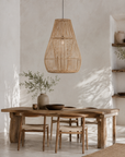 Dining area with wooden table and chairs, wicker pendant light, and neutral decor.