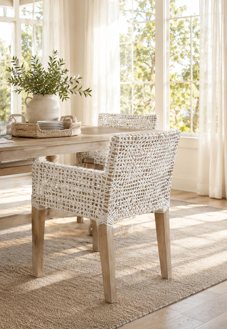 Dining room with wicker chairs and a table, natural light streaming in.
